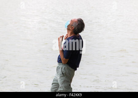 Vietnamese man practicing tai chi sur la rive du lac Hoan Kiem de Hanoi, un masque contre la pollution,Vietnam Banque D'Images