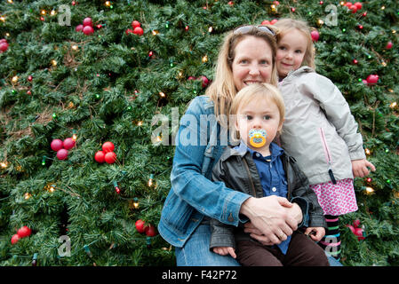 Mère et enfants se tenant en face de l'arbre de Noël en plein air, portrait Banque D'Images