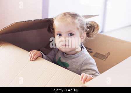 Petite fille jouant en boîte carton, portrait Banque D'Images