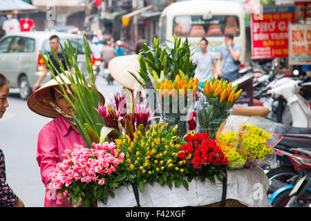 Dame vietnamienne marchande de fleurs dans le vieux quartier de Hanoi, vente de fleurs de l'arrière de son vélo.Vietnam Banque D'Images