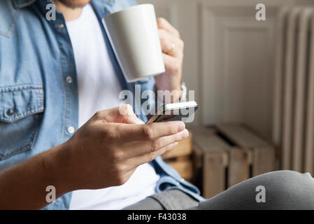 La capture de l'homme à vos messages tout en ayant le café du matin Banque D'Images