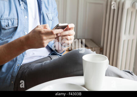 La capture de l'homme à vos messages tout en ayant le café du matin Banque D'Images