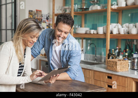 Couple using digital tablet in kitchen Banque D'Images