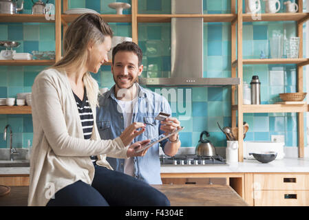 Couple using digital tablet in kitchen Banque D'Images