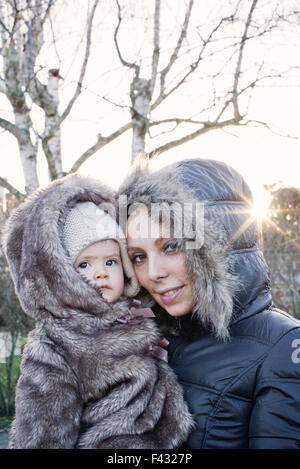 Mother holding baby girl en plein air, les deux portant des manteaux d'hiver, portrait Banque D'Images