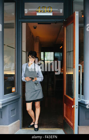 Jeune serveuse portant un tablier à un restaurant de la ville. Banque D'Images