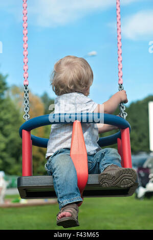 Mignon bébé garçon regardant en arrière on swing Banque D'Images