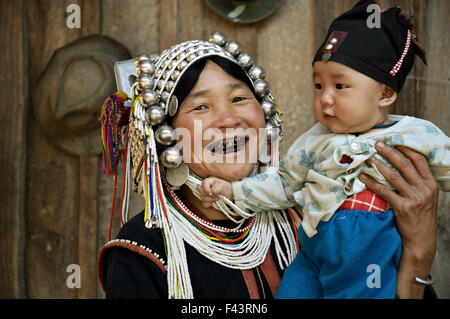 Femme Akha avec dents noir portant un bébé dans un village autour de Kengtung (Kyaingtong), l'État de Shan, Myanmar Banque D'Images