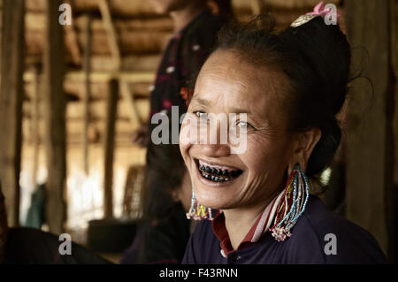 Femme de la tribu avec dents noir Ann sourit à l'intérieur de sa maison dans un village autour de Kengtung, Shan State, Myanmar Banque D'Images