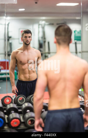 Homme debout devant un grand miroir Banque D'Images