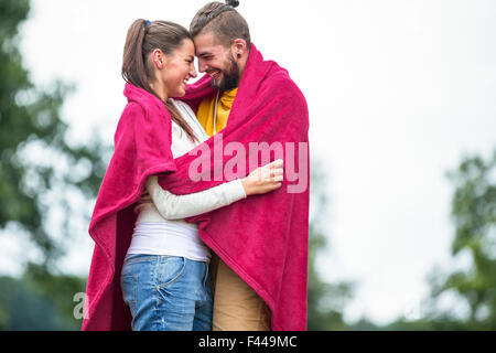 Heureux couple hugging under blanket Banque D'Images