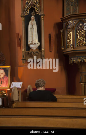 Femme a un moment de prière sous la statue de la Sainte Vierge dans une église catholique à Zielona Gora, Pologne. Banque D'Images