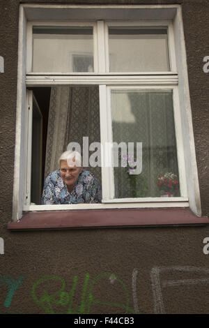 Homebound vieille femme socialise avec les passants dans la fenêtre de son appartement Zielona Gora, Pologne. Banque D'Images