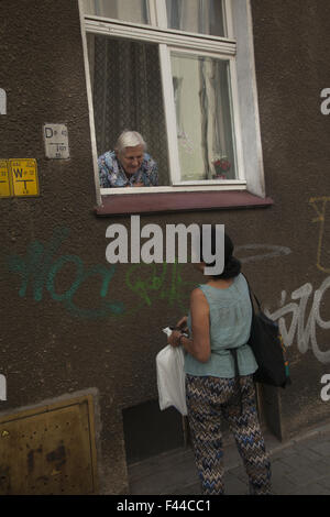 Homebound vieille femme socialise avec les passants dans la fenêtre de son appartement Zielona Gora, Pologne. Banque D'Images