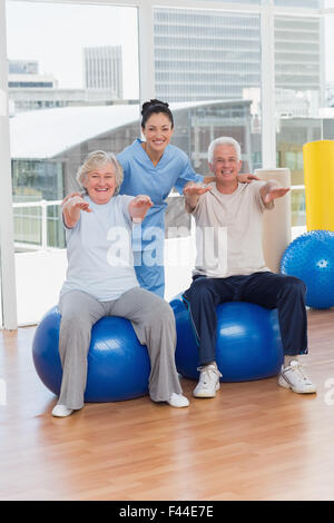 Senior couple on exercice balle avec formateur Banque D'Images