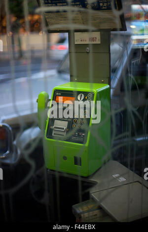Téléphone public payant avec booth derrière un téléphone vert verre vandalisés Banque D'Images