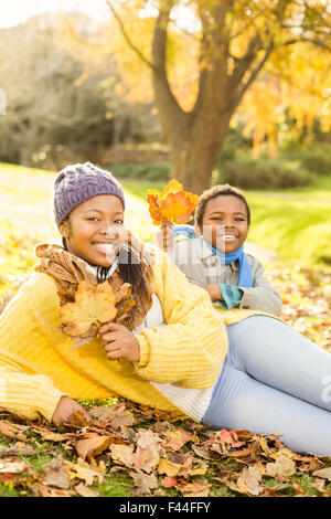 Jeune mère avec son fils assis dans les feuilles Banque D'Images
