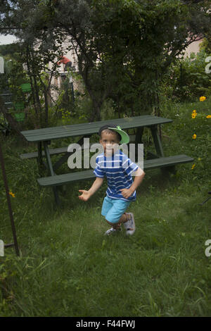 Jeune garçon joue seul à la maison dans l'arrière-cour à Zielona Gora, Pologne. Banque D'Images