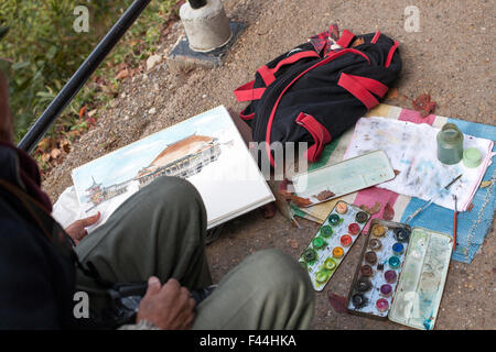 Aquarelle set répartis sur un sol en béton avec la peinture et les jambes et les mains de l'artiste Banque D'Images