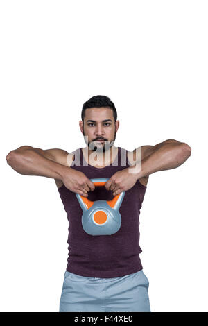 Homme sérieux musculaire du levage d'une kettlebell Banque D'Images