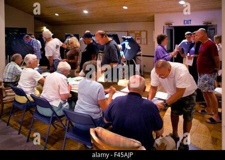 Les résidents d'un Laguna Niguel, CA, la communauté en copropriété la queue aux bureaux de scrutin à leur club house le jour de l'élection le soir. Remarque les bénévoles et des machines à voter. Banque D'Images