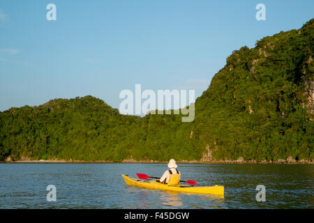 Homme dans un kayak sur les eaux autour de l'île de Cang do, baie de Bai tu long dans la baie de Ha long, Vietnam, Asie Banque D'Images