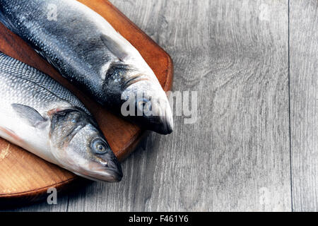 Le Bar Cru poissons sur le sol en bois Banque D'Images