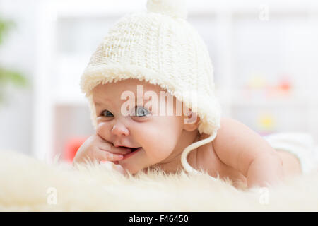 Cute little baby à la recherche dans l'appareil photo et portée en white hat. Banque D'Images