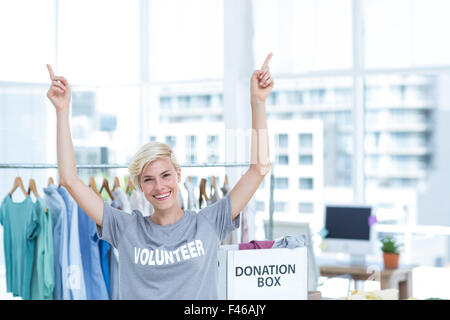 Happy blonde volunteer pointant vers le haut Banque D'Images