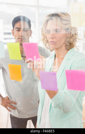 Young businesspeople pointing at sticky notes Banque D'Images