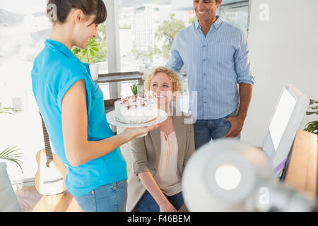 Woman blowing out candles on cake Banque D'Images