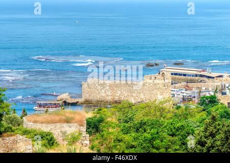 La ville ancienne et historique port de Byblos au Liban. Une vue sur les anciens remparts qui l'entourent et d'un bateau entrant dans le port de Banque D'Images