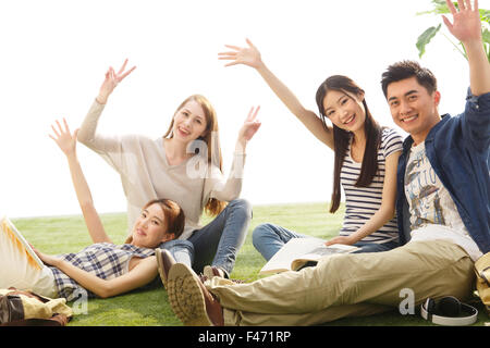 Les jeunes gens assis sur la pelouse cheering Banque D'Images