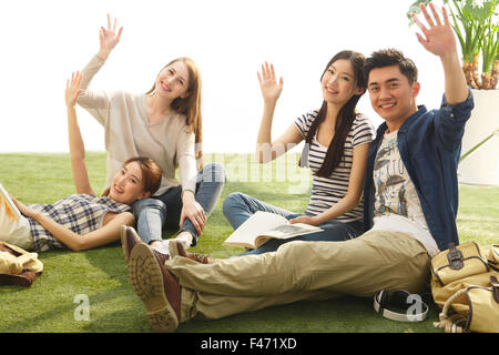 Les jeunes gens assis sur la pelouse cheering Banque D'Images