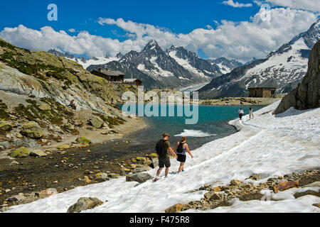 Les touristes à névé au lac Blanc lac de montagne dans la réserve naturelle nationale des Aiguilles Rouges, Refuge du Lac Blanc mountain hut Banque D'Images