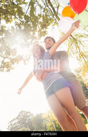Cute couple hugging and holding balloons in the park Banque D'Images