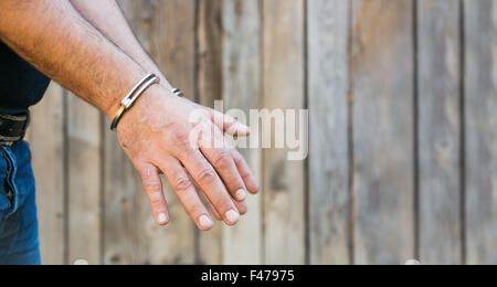 Arrestation, close-up shot man's hands avec des menottes en face du mur de bois en planches avec copy-space Banque D'Images