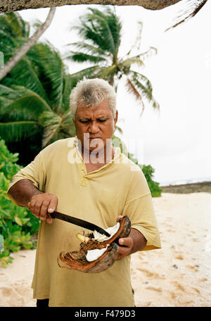 L'homme de l'ouverture d'une noix de coco sur la plage, à Tuvalu. Banque D'Images