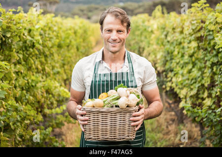 Smiling farmer holding un panier de légumes Banque D'Images