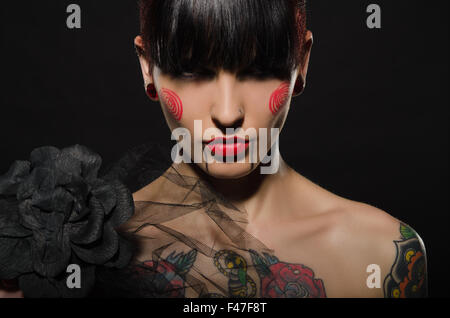 Charmante brunette tatouée avec fleur noire Banque D'Images