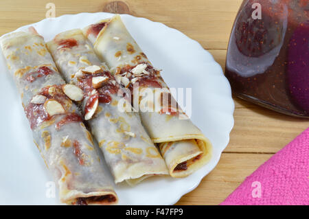 Crêpes sucrées avec de la confiture de fraise et de noisettes servi sur la plaque Banque D'Images