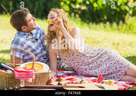 Jeune couple eating grapes à un pique-nique Banque D'Images