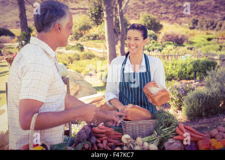 Smiling brunette agriculteur vendant des légumes et du pain Banque D'Images