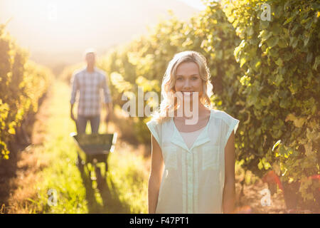 Portrait of smiling woman standing in front ou son homme poussant une brouette Banque D'Images