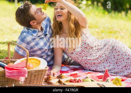 Jeune couple eating grapes à un pique-nique Banque D'Images