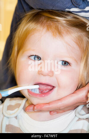 Bébé / enfant l'avoir brossé les dents de lait avec une brosse à dents / brosse à dents - par sa mère. Banque D'Images
