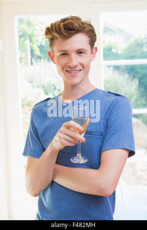 Handsome young man smiling at camera et holding glass of champagne Banque D'Images