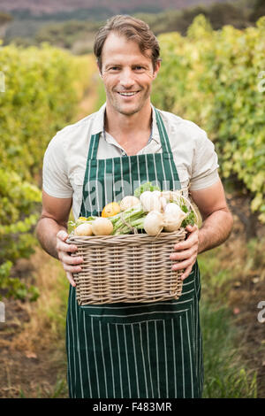 Smiling farmer holding un panier de légumes Banque D'Images