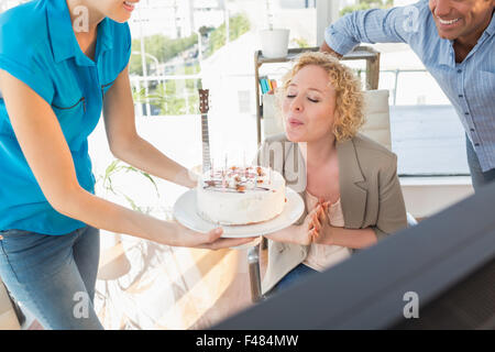 Woman blowing out candles on cake Banque D'Images