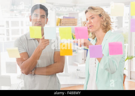 Young businesspeople pointing at sticky notes Banque D'Images